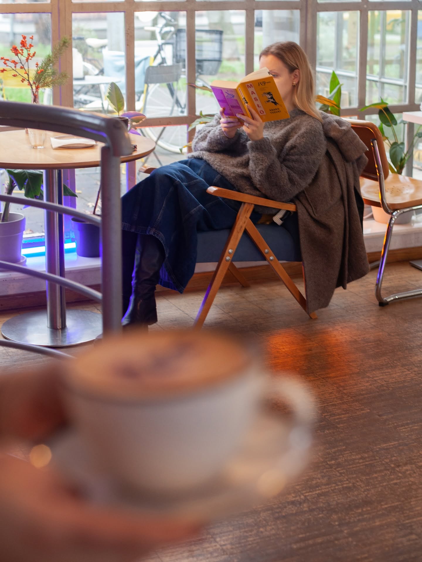 Jasny kącik Cafe Luis przy oknie, z fotelami, stolikami i gościem czytającym książkę